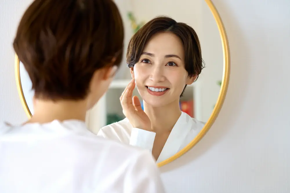 鏡を見てほほ笑む女性の画像
